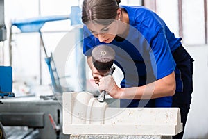 Woman Stonemason carving pillar out of stone in workshop