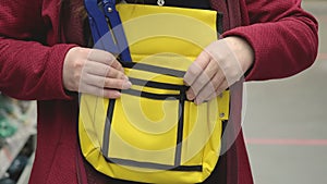 Woman in store chooses sturdy yellow tool bag. In bag is blue adjustable wrench