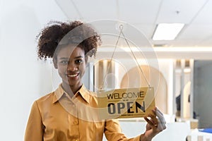 Woman store owner turning open sign broad through the door glass and ready to service. Small business woman owner turning the sign