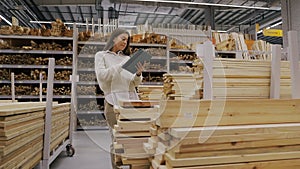 Woman Storekeeper Working with Tablet in Lumber Warehouse or Hardware Store