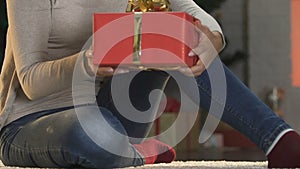 Woman straightening bow on big giftbox, preparing presents to Christmas holidays