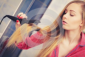 Woman straightening her long blond hair
