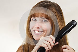 The woman straightens hair the curling iron