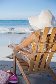 Woman in straw hat relaxing in deck chair on the beach
