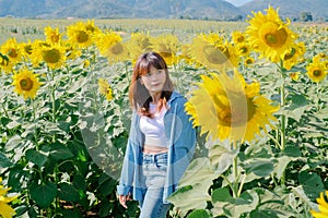 A woman in a straw hat is standing in a large field of sunflowers. stands in flowering field. Summer time, lifestyle, travel and