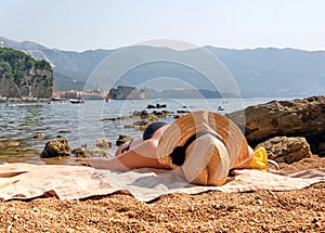 Woman in a straw hat sunbathes on the beach of Budva, Montenegro