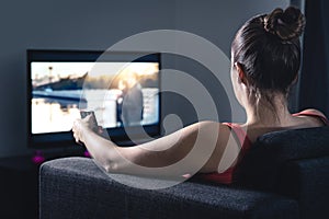 Woman streaming movie or watching series. Person using smart tv remote control to choose film or change channel.