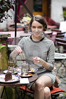 Woman at street cafe brews tea and smile