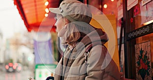 Woman, street and waiting for taxi with phone in rain, thinking or winter for travel, transport and cab in city. Girl