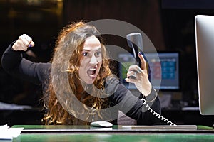 Woman in stress in front of computer. A woman is shouting into the phone`s phone