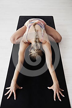 A woman stretches her back and arms in a yoga posture.