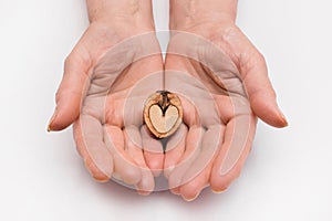 Woman stretches out her hands with halve of a walnut in the form of a heart on a white background, isolated. Nut concept