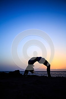 Woman stretches yoga sunset silhouette