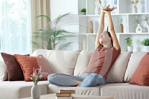Woman stretching arms at home on a couch