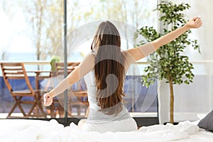 Woman stretching arms and waking up in bedroom