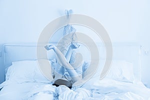 Woman stretching in bed with legs raised up high in bedroom