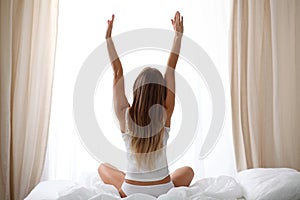 Woman stretching in bed after wake up, back view, entering a day happy and relaxed after good night sleep. Sweet dreams