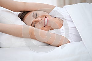 Woman stretching in bed after wake up, entering a day happy and relaxed after good night sleep. Sweet dreams, good