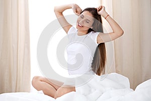 Woman stretching in bed after wake up, entering a day happy and relaxed after good night sleep. Sweet dreams, good