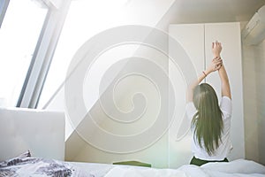 Woman stretching in bed after wake up in morning with sunlight