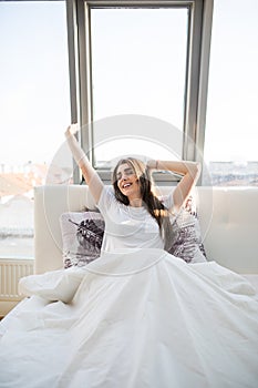 Woman stretching in bed after wake up in morning with sunlight