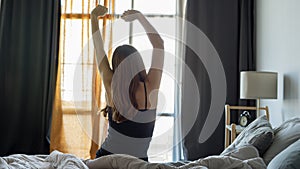 Woman stretching in bed after waking up