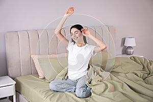 Woman stretching on comfortable bed with linens