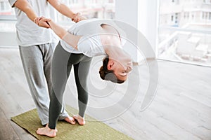 Woman stretching and doing acro yoga with partner in studio