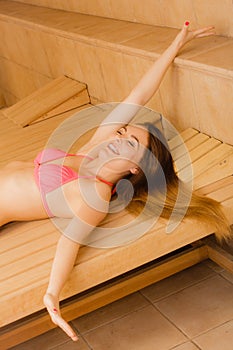 Woman stretching enjoying relaxing in spa sauna.