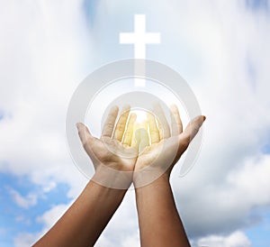Woman stretching hands towards cross silhouette on blue sky, closeup. Praying concept