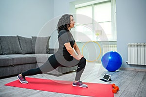 Woman stretching her leg and back. Girl using tablet looks online master class. Training at home