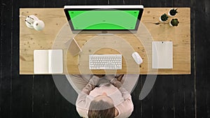 Woman stretching her tense nape in the office in front of the computer monitor. Green Screen Mock-up Display.