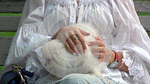 Woman stretching her white hairy dog.