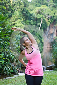 Woman stretching left side of body after exercising in outdoor park