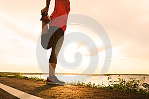 Woman stretching leg muscle preparing for sunset trail run