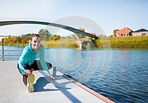 Woman stretching leg muscles outdoors by the river