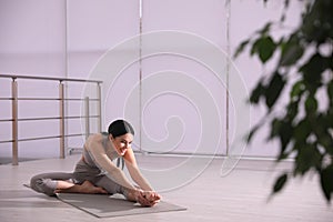 Woman stretching leg in yoga studio. Janu Sirsasana pose variation
