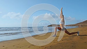 Woman stretching legs and hamstrings doing Standing Forward Bend Yoga stretch pose on beach. Fitness woman relaxing and