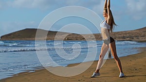 Woman stretching legs and hamstrings doing Standing Forward Bend Yoga stretch pose on beach. Fitness woman relaxing and