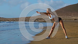 Woman stretching legs and hamstrings doing Standing Forward Bend Yoga stretch pose on beach. Fitness woman relaxing and