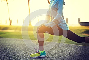 woman stretching legs before run at tropical park