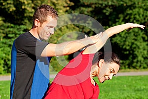 Woman stretching with personal trainer outdoors