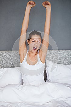 Woman, stretching and portrait in bed with yawn in morning and wake up with fatigue after resting. Tired, girl and