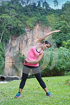 Woman stretching right side of body after exercising in outdoor park