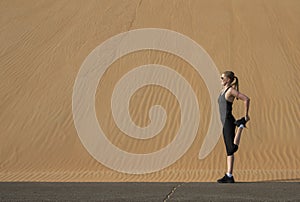 Woman stretching after a run in a Liwa desert