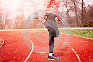 Woman stretching on a running track.