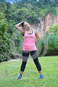 Woman stretching side of neck after exercise in outdoor park