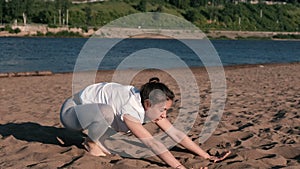 Woman stretching yoga on the beach by the river in the city. Beautiful view. Vinyasa.