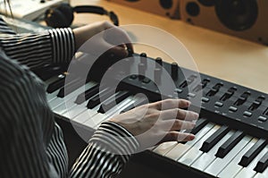 A woman in a striped shirt plays the synthesizer and tunes it.