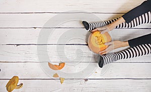 Woman in striped stockings preparing pumpkin for Halloween